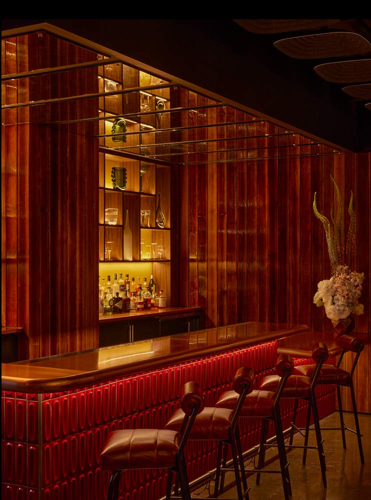 A bar at AMA by Brad Kilgore shows red chairs and wooden walls in a high-energy dining experience