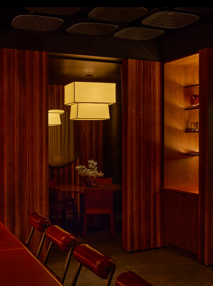 A room at AMA by Brad Kilgore features red leather chairs and wooden walls in an upscale lounge & social club atmosphere.