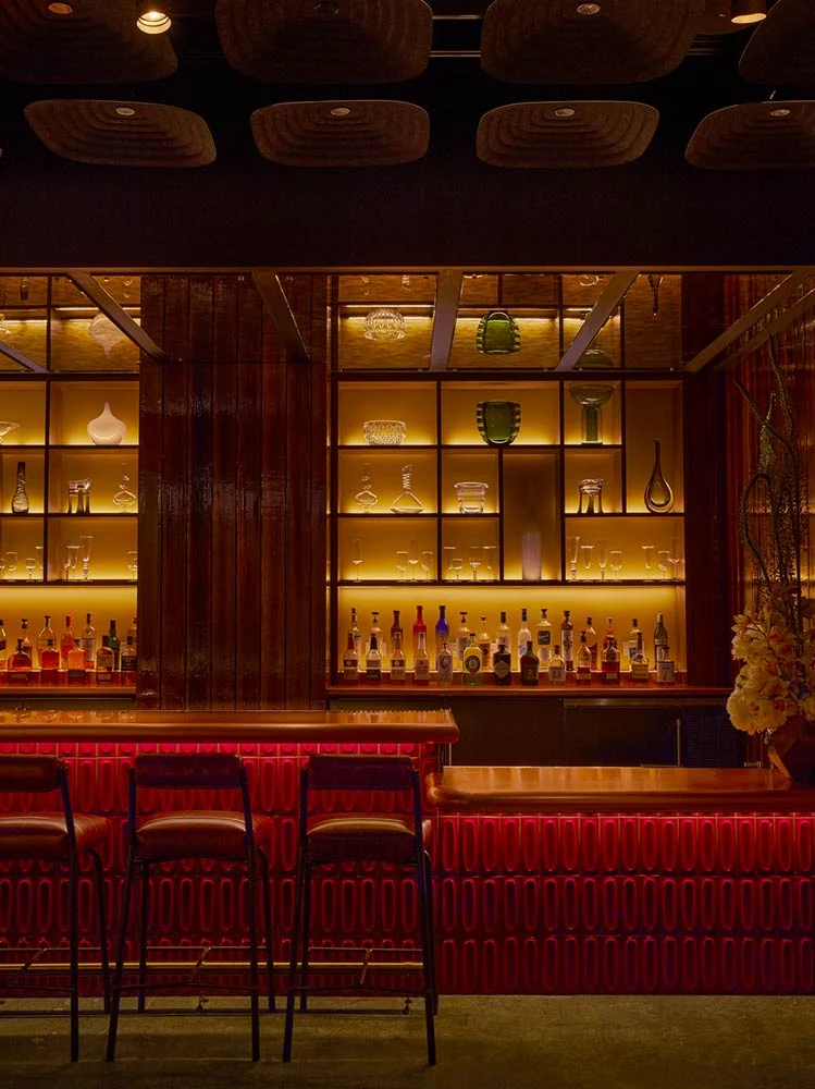 A bar inside AMA by Brad Kilgore offers red chairs and wooden walls for a high-energy dining experience.
